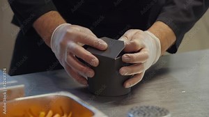 Chef manually closing the prepared noodle food take out box. Lots of delicious noodle food placed into the small take out box. Cook sends the noodle food take out box for delivery to customers.