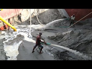 Sand is being unloaded from large ships with powerful dredger machines