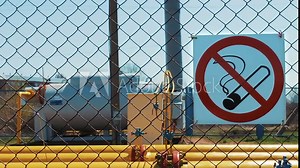 Oil plant. Warning on the fence about the ban on smoking. Danger of open fire. Oil and gas industry. Storage tanks for natural gas storage and purification. Pipeline with a manometer. Gas pressure
