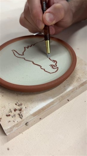 “Sgraffito is a decorative technique that involves cutting away parts of a surface layer (such as plaster or clay) to reveal a different colored ground. The word sgraffito comes from the Italian word “graffiare” which means to scratch.” To produce this effect, I made small plates using a dark flagstone clay and then painted on a thin layer of b-mix white slip. After letting the plates sit for a couple days wrapped under a plastic sheet, they are stiff enough to carve into without being too dry. 