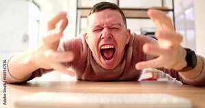 Crazy excited grimacing man types on computer keyboard at table slow motion. Weird internet fraud discusses with users online. Emotional hacker cracks website