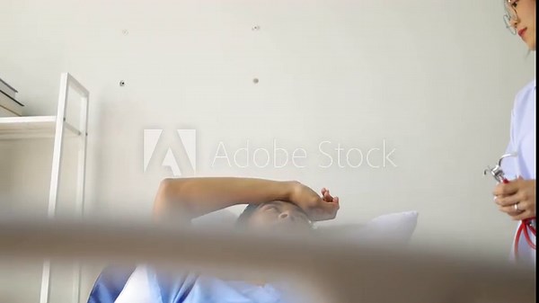 Female doctor is examining a male patient in a hospital bed. Doctor diagnosing patient using stethoscope.