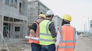 Back view of Civil engineer or architect and foreman, colleague stand talking wear safety helmet. Before will start work and walking survey on construction site. Building and Real estate concept.