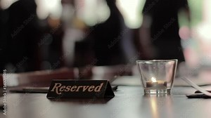 A server places a reserved sign on a restaurant table at a classy dining lounge.