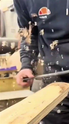 smoothing the long wood board surface using a sharp hand chisel tool inside the carpentry workshop