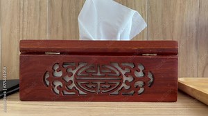 Close up of woman hands pulling tissues from white plastic box in dental clinic. White paper towel dispenser on the wall. Health care and prevention