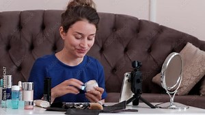Woman vlogging on mobile phone, presenting and reviewing cosmetics accessories and products online