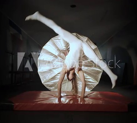 Female gymnast in a tight white leotard falling while attempting a trick