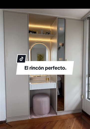 Closet con tocador de maquillaje fabricado en Madecor RH, tocador en madera con laca poliuretano, manijas largas en latón dorado y espejo de arco con sensor táctil de iluminación LED. Iluminación LED integrada en la parte superior del nicho y puerta con vidrio reflectivo que amplía visualmente el espacio. El puf en tono rosado añade calidez y personalidad al conjunto. 🤍✨ 💡 En diseño de interiores, la coherencia entre materiales, tonos y accesorios es lo que transforma un mueble funcional en un