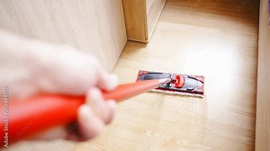 Cleaning floor with Microfiber Dust Wet Mop in slow motion 4K. Person point of view of dust wet mop in focus moving on the ground leaving the wet floor. Hand holding in left part of the frame.