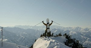 Snowboarder freerider stands on top of the mountain, raises arms into air, happy and drunk on life. Extreme freeride snowboarding down the mountain slope. Adventure, freedom, success, winter sport