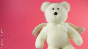 Stuffed and fluffy teddy bear toys with angel wings playing and dancing on a pink background.