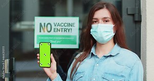 Portrait of woman holding smartphone with chroma key. digital health passport app with covid-19 certificate. Proof of vaccination. No vaccine no entry service. Green screen