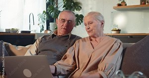 COMPUTER LITERACY FOR OLDER PEOPLE Happy senior retired 70s man and woman learn to use laptop to shop online at home.