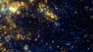 Golden and blue particle effects glitter gracefully on a dark background. Premium abstract footage perfect for creative storytelling.