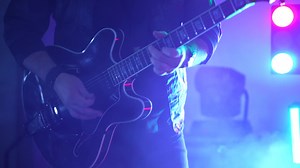 Rock Guitarist Shreds Electric Guitar on Concert Stage - Dynamic Performance by Guitarist in Rock Band - Energetic Live Music Show with Electric Guitar Solo - Vibrant Stage Presence in Rock Concert
