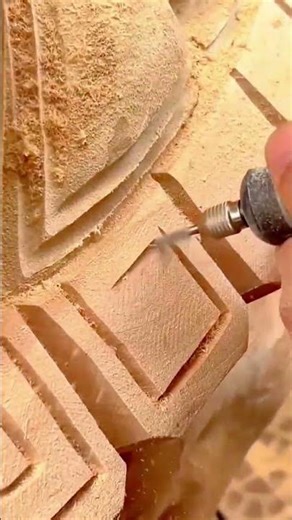 carving intricate geometric patterns and square shapes into a stone surface using a rotary tool