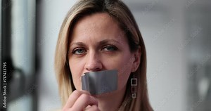 Assertive woman removes tape from mouth, feeling relieved and free to speak