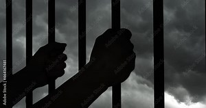 Prisoner hands holding prison cell bars with dark storm clouds background.
