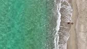 Aerial video of a young woman sunbathing at the sandy beach