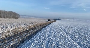 Green Tractor Plowing Snow in Rural Landscape