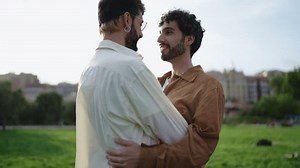 Affectionate gay couple kissing tenderly, immersed in moment of love, with soft sunset in serene park. Romantic embrace between two men, sharing kiss, symbolizing love and LGBTQ+ pride