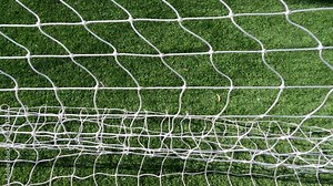 Soccer Goal Net on Green Sports Field. Looking down at a white soccer goal netting as part of a soccer backstop net structure. The sports netting waves in the wind.