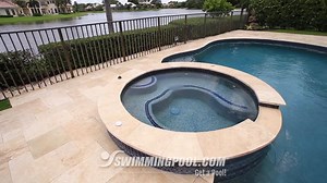 The raised spillover spa on this kidney shaped pool is rimmed with NPT - National Pool Tile's Luciana tile in Terra Blue. The StoneScapes Aqua Blue finish makes the water sparkle in the sun with a Touch of Glass! | SwimmingPool.com