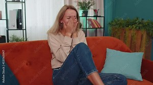 Scared caucasian girl screams from stress tension problems panic horror hopelessness fear surprise shock expresses gestures rage. Furious unhappy young woman at home apartment room sitting on couch