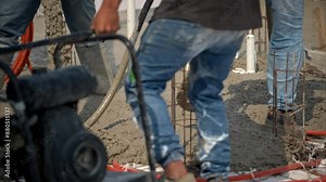 Slow motion of construction workers carrying around a concrete vibration machine while fresh concrete mix is being poured to make a bald in Mexico