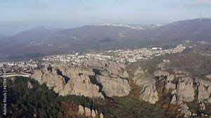 Straffe aerial drone shot panning from right to left, showing a panoramic view of the Belogradchik natural rock formations with the Balkan mountains in the backgorund, in Vidin province, Bulgaria.
