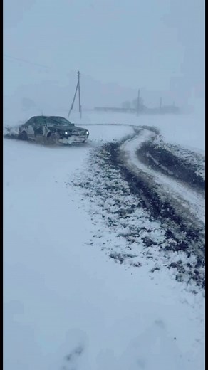 Stranded Sedan Struggles in Snowy Conditions