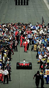 At the 2000 Italian Grand Prix, an early track invasion by fans celebrating Ferrari’s success created a dramatic scene as drivers returned to the pits. Michael Schumacher, who had just secured a critical victory in his championship campaign, navigated through the crowd, avoiding any incidents. The event highlighted the passionate but sometimes overwhelming enthusiasm of F1 fans at Monza, known as the “Temple of Speed.” | Motorchive