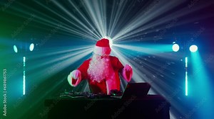 DJ Santa Claus mixing tracks in a nightclub at a Christmas and New Year party or Corporate events. Senior disc jockey as Santa listening music, headphones, laptop, mixer controller player, turntable.