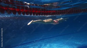 Coordinated movements. Competitive woman, professional female swimmer training in swimming pool indoor. Underwater view. Concept of sport, endurance, competition, energy, healthy lifestyle