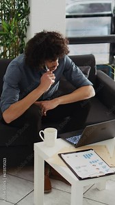 Vertical Video Creative employee looking to develop program in open floor plan office, working with past annual statistics to create new development strategy. Businessman thinks about startup growth.