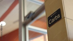 A sign that reads carbs with an arrow pointing to the left in cafeteria