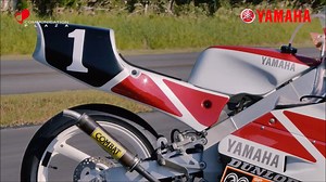 初代のTZ125は、インドネシアの国内レース用に投入された排気量100ccの工場レーサーをベースに開発され､1979年から３年間ほど生産されました。その後ぱったりと開発が止まったまま10年以上が経過した1993年、突如として２代目のTZ125のプロトタイプが全日本選手権に登場しました。ライダーはSP忠男レーシングチーム所属の加藤義昌選手。前年途中まで250ccクラスに参戦していましたが、開発ライダーとして起用されるや、実戦テストとして参加した全日本選手権の初戦で優勝という衝撃的なデビューを果たしたのです。加藤選手はその後も開発テストの合間を縫ってレースに参戦し、開幕戦の勢いそのままに参戦した10戦中６回の優勝でチャンピオン獲得という快挙まで成し遂げました。 エンジンはTZ250と同様のボア・ストロークを採用し、シリンダ・ピストン等の素材を共通化した事でコスト低減を図る一方で、初代モデルの弱点であった単気筒特有の振動を低減するために一軸バランサーを採用し、レーサーの必須アイテムである乾式クラッチやカセット式トランスミッションを標準装備するなど、必要な部分には惜しみなくコストを掛けるという