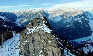 drone flight alpine summit ridge natural rock texture snowy hilly valley with sunny sky picturesque landscape. Aerial view winter mountain epic scenery high cliff peak freeze glacier slope