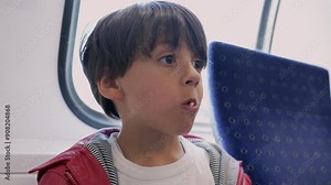 Young boy eating a pretzel on a train, showing curiosity and enjoyment as he catches the dropped pretzel and puts it back in his mouth, simple pleasures of childhood