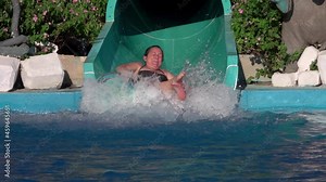Beautiful girl riding a water slide. happy woman going down on water slide in the aqua park. Summer Vacation. Weekend on resort Stock Video