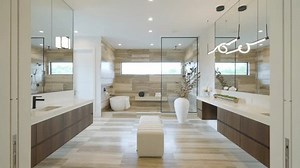 Modern bathroom interior with mirror, double vanity sinks and freestanding bathtub. Design features light colored, wood accents and clean lines. Contemporary and luxurious