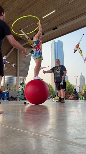 Circus Performer Balances on Ball With Hoop While Men Juggle Pins - 1519380-2