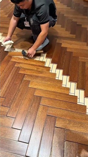 Worker installing herringbone patterned wooden flooring