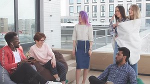 Lounge outdoor zone at modern office. People discussung working process sitting on soft poufs over glass urban skyscrapers background Stock Video