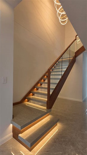 Coffs Stairs and Balustrade on Instagram: "Dark rich timber, crystal-clear glass, stone steps and soft under-step LED lighting — every detail working together to give this staircase some serious royal, Oceans Eleven energy. First time using silica-free stone on a staircase and it absolutely delivered. Finished in a beautiful home with clients who genuinely appreciate the details. #stairs #custom #timber"