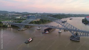 Aerial footage view of where many ships pass by on the Mahakam River while passing the Mahakam Bridge from below