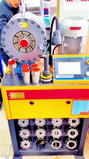 Hand positions metal fitting with red cap into hydraulic crimping machine head