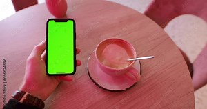 Chroma key of smartphone in a male hand, using and scrolling a mobile phone with empty green screen