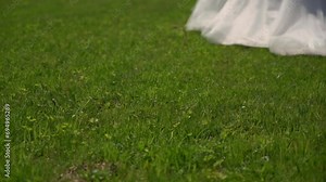 A bride in a long white wedding dress and high-heeled shoes walks on lawn. Wedding ceremony, reception. Woman run away slowmotion.
